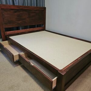 Dark stained wooden bed with headboard and storage drawers pulled out