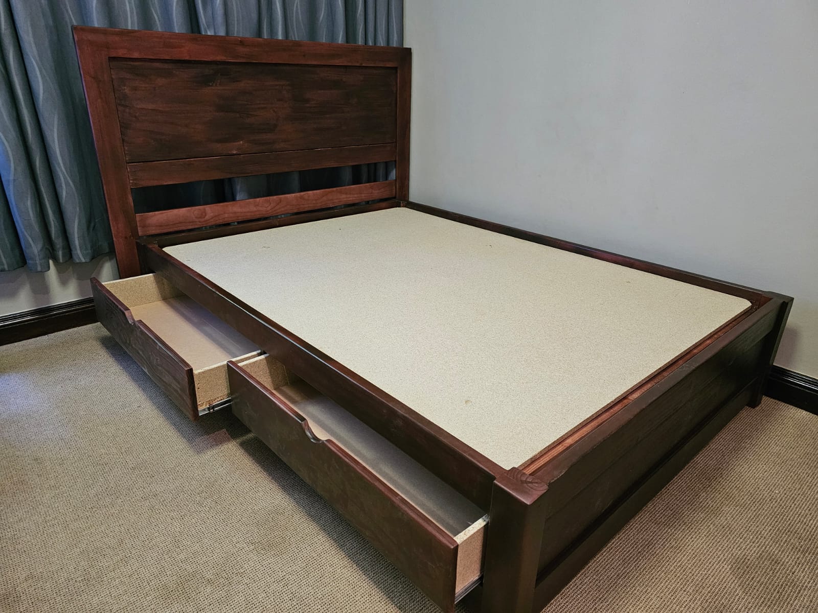 Dark stained wooden bed with headboard and storage drawers pulled out