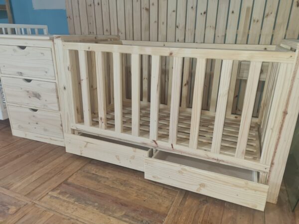 Raw wooden crib compactum with storage drawers angled view