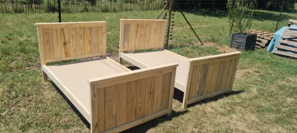 2 single raw wooden kids beds with headboards and footboards angled view