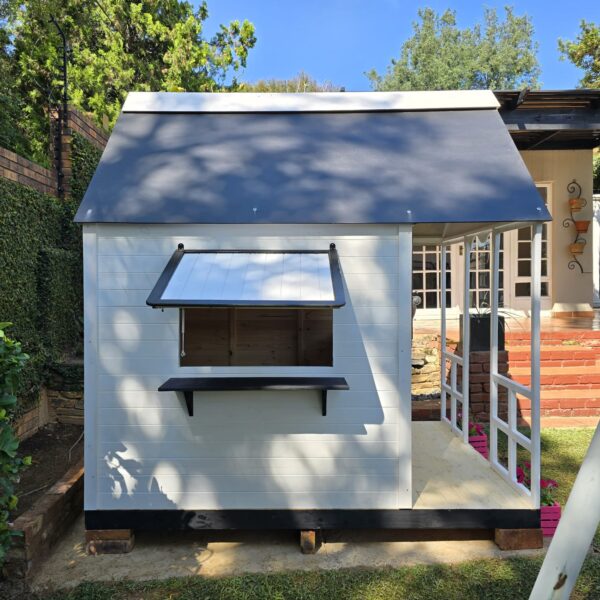 White and black wooden playhouse with pink flower crates side view