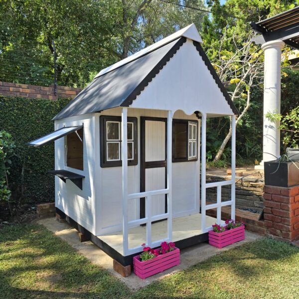 White and black wooden playhouse with pink flower crates angle view