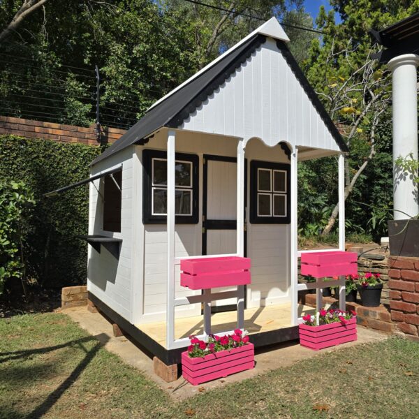 White and black wooden playhouse with double pink flower crates side angle view