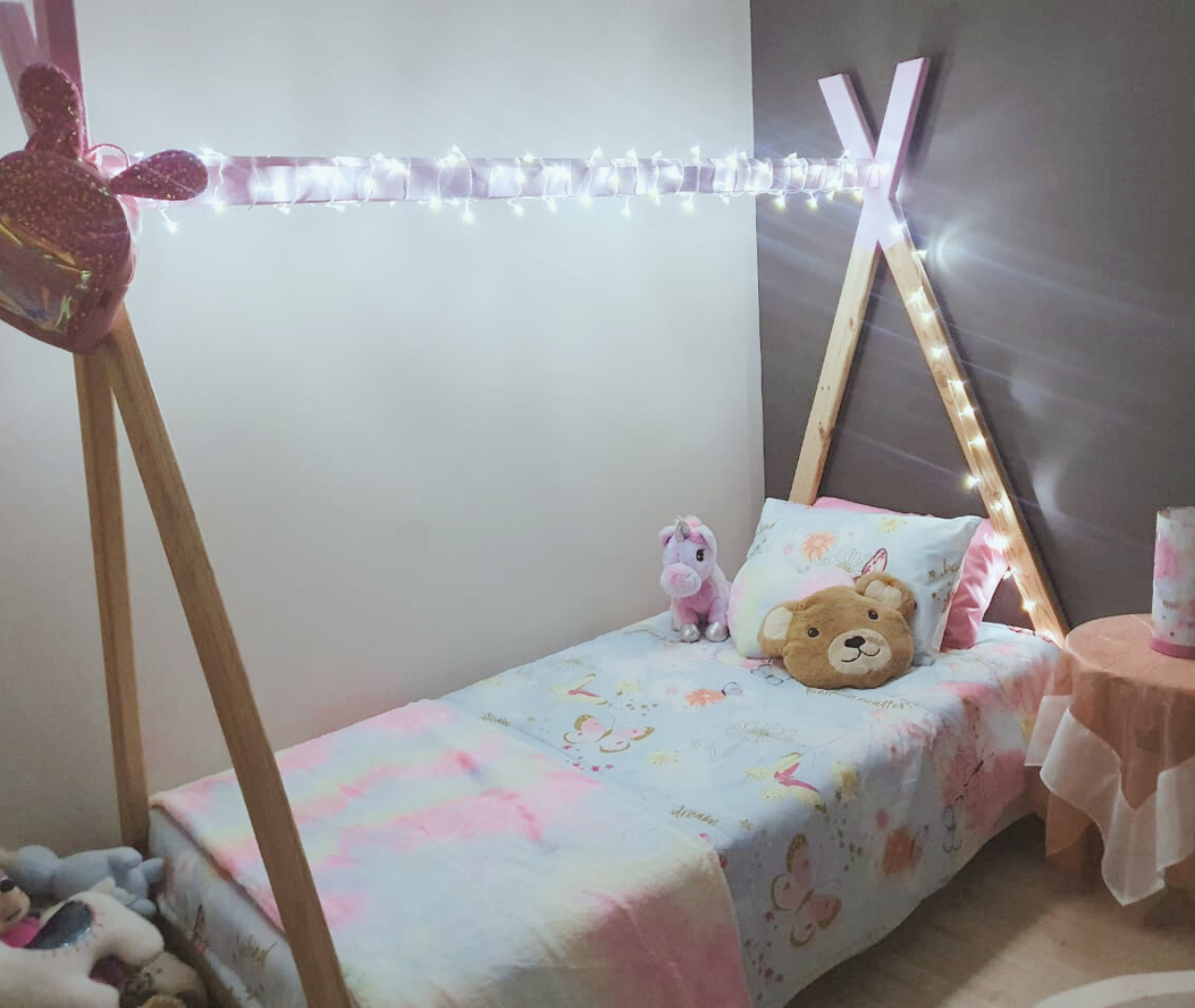 Simple teepee bed with lights and soft blue and pink bedding