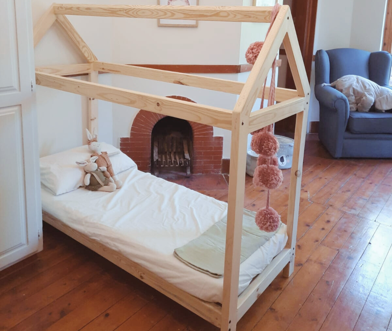 Raw pine kids house bed in room with wooden floors and one seater couch