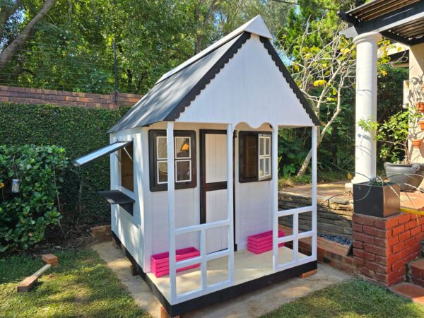 White and black wooden playhouse with pink flower crates angled view